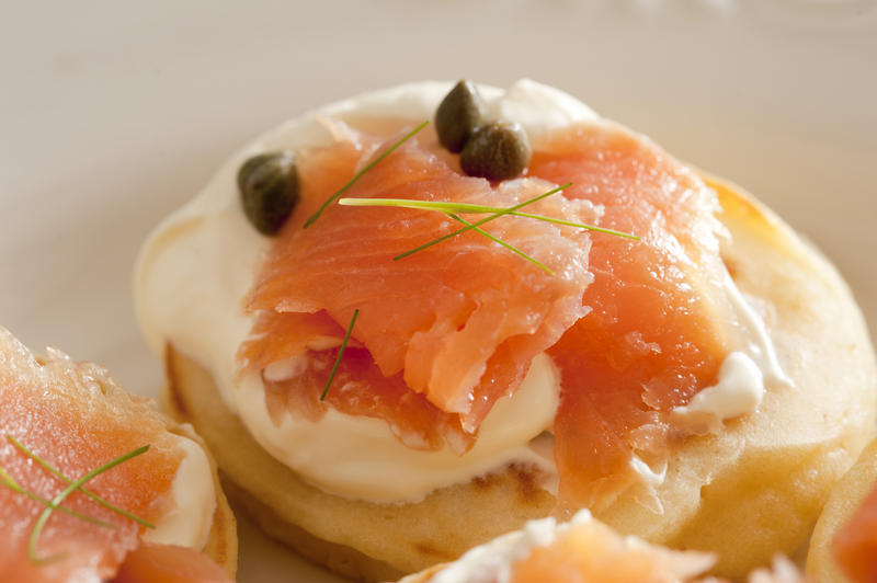 Macro close up on biscuit with creme cheese, dill leaves, capers and pink salmon meat as appetizers