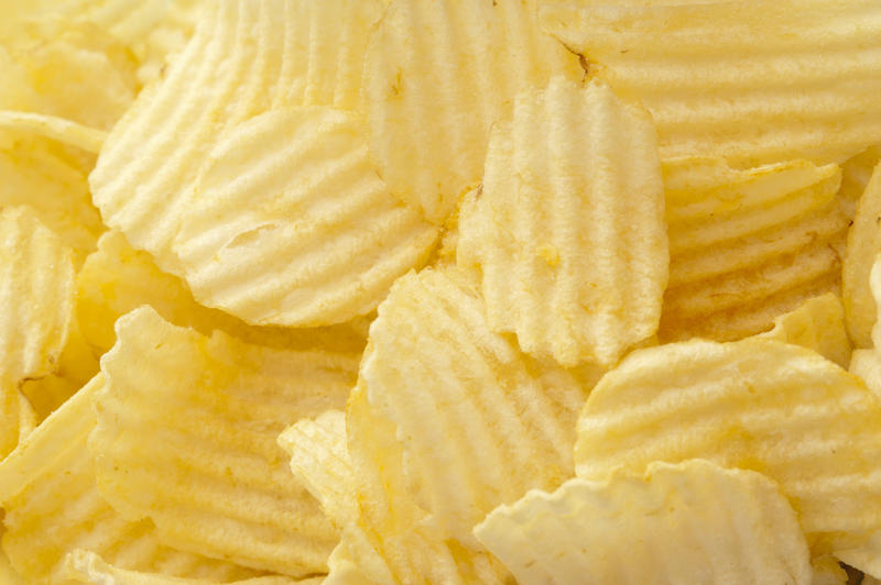 Delicious plain ruffled potato chips piled unceremoniously one atop another