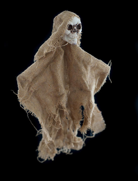 Spooky single burlap Halloween skeleton doll over black background for theme about ghosts