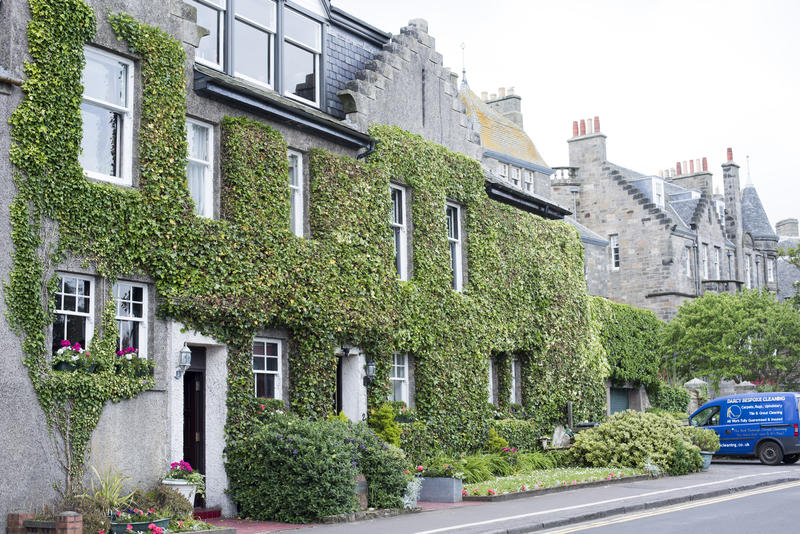 Row of creeper covered old stone houses, St Andrews, Scotland with a blue van parked in front