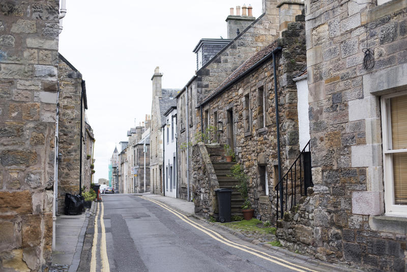 Empty narrow paved road between old stone houses in the town of Saint Andrews, Scotland, Europe
