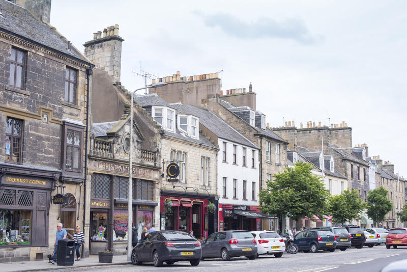 Various parked cars and tourists along busy small town street in Saint Andrews Scotland