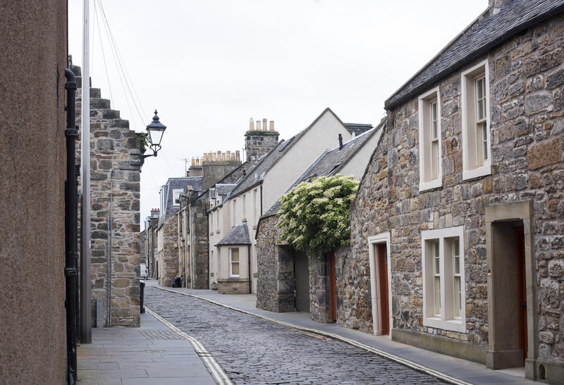 Quaint old stone cottages lining a narrow street in St Andrews, Scotland on an overcast day