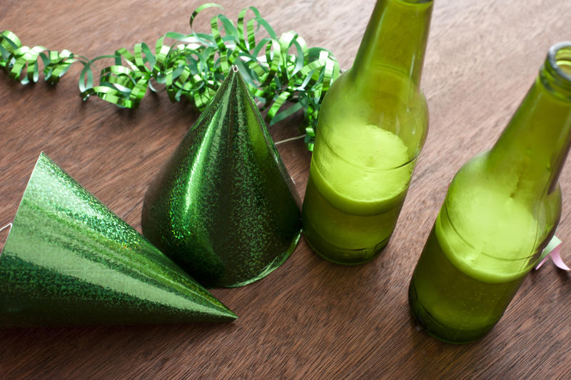 Green ribbons, conical hats and bottles of beer on wooden table and white background with copy space for saint patricks day concept