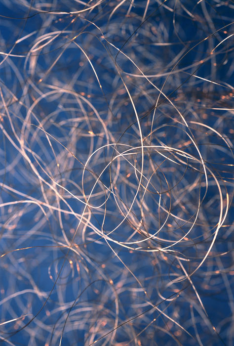 Steel wires tangled and looped close up with blue background for concept about recycling or electronic waste