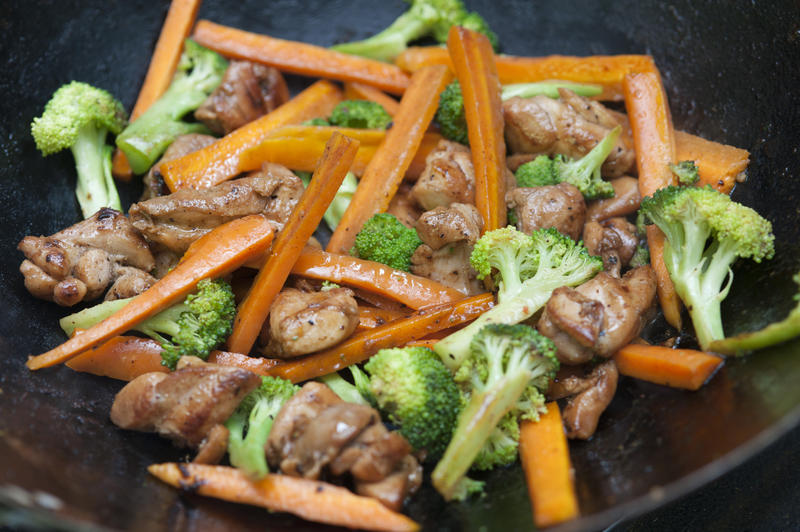 Tasty Asian stir fry cooking in a wok with diced carrots and broccoli and thin slivers of marinated spicy meat