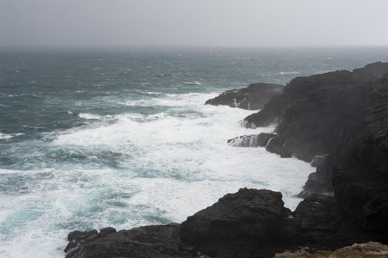 large waves and foaming water breaking of a rocky cliff coastline