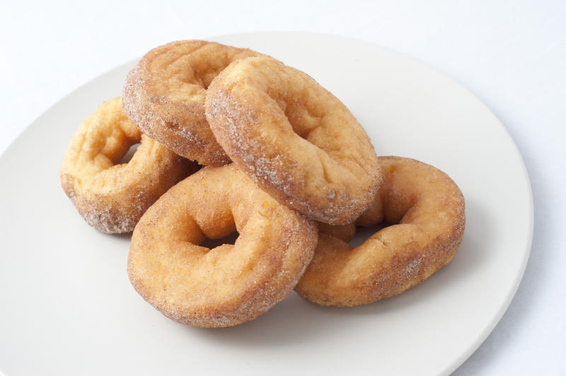Plate of fresh ring donuts or doughnuts sprinkled with sugar for an unhealthy, but tasty, breakfast