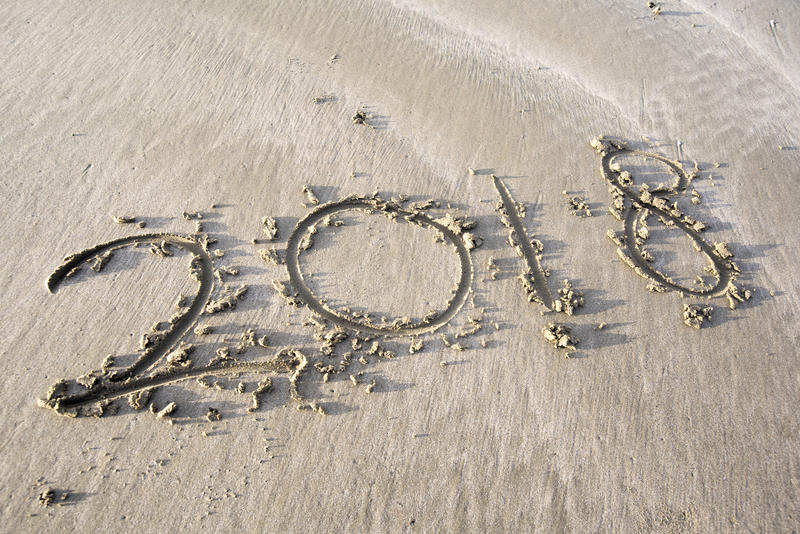 Concept of a summer holiday by the beach, the year 2018 written in sand