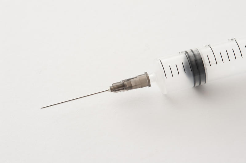 Close up of empty syringe and needle over white background with light set down shadow