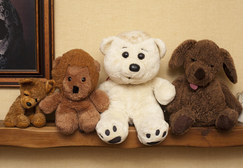 Row of assorted soft plush toys on a wooden shelf indoors in a home for a young child or baby