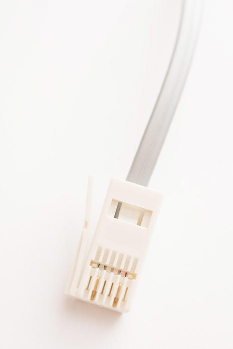 White telephone plug connector with wire close-up on white background