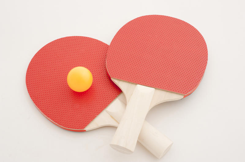 High Angle View of Pair of Red Tennis Table Paddles with Yellow Ball in Studio with White Background with Copy Space