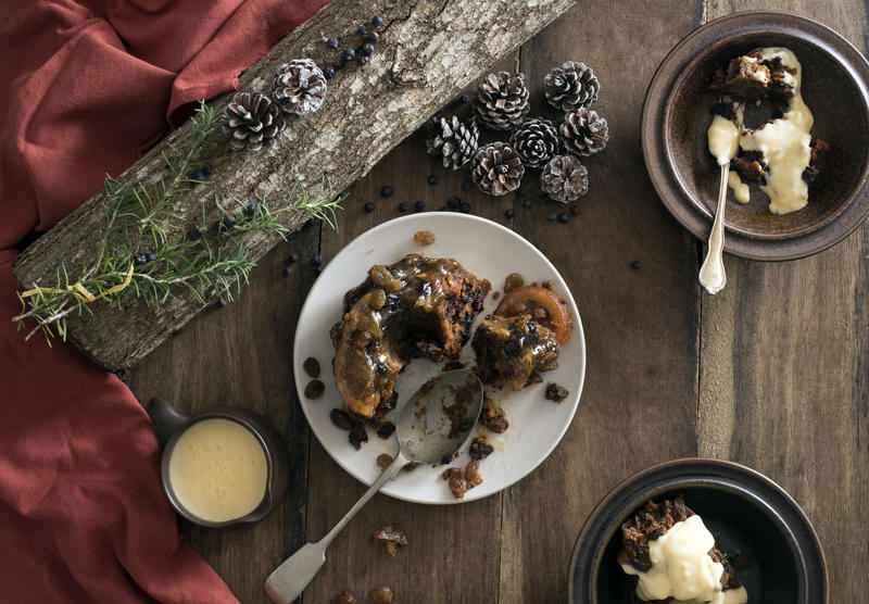 Flat lay Christmas pudding with brandy sauce served in two bowls on a festive holiday table with decorations