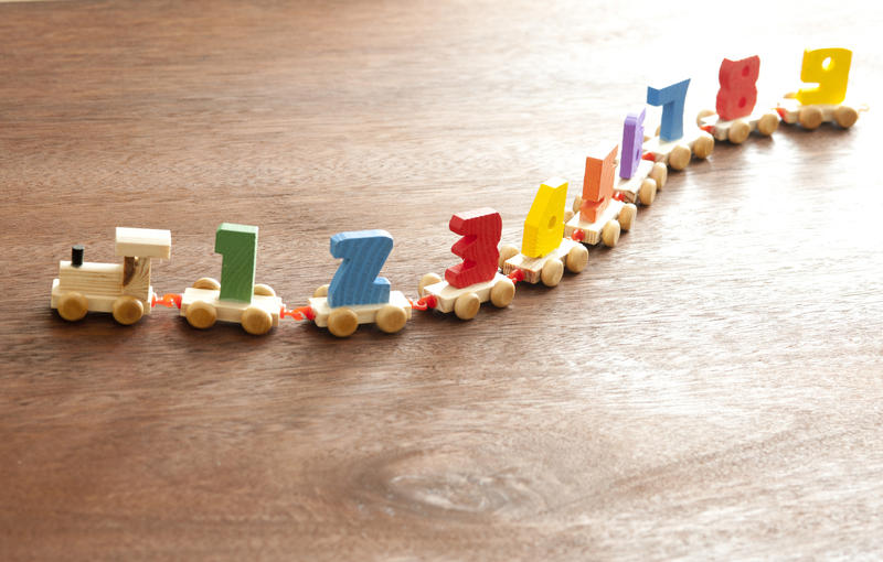 Undulating number train kids educational toy with colorful wagons and numbers 1 through 9 on a wooden floor with copy space