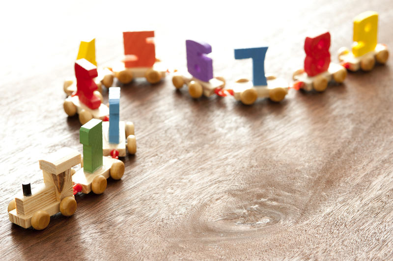 Kids wooden toy numbers train with a little engine pulling carriages each with a number 1 through 9 for teaching basic counting and arithmetic