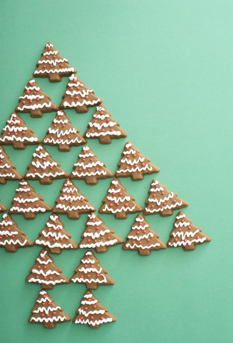 Gingerbread Christmas tree still life with traditional tree shaped Xmas cookies arranged on a green background with copy space