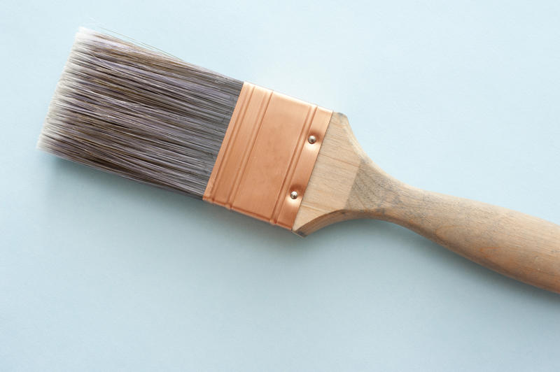 Single wooden and copper thick wall paint brush over blue background with copy space