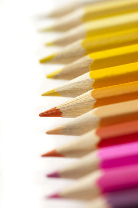 Selective focus extreme close up view on bright pink, orange and yellow sharpened colored pencils