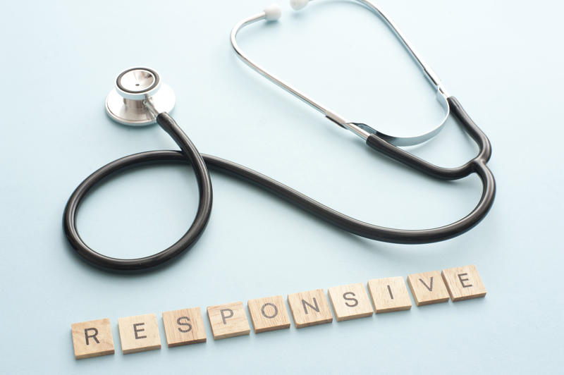 High Angle Close Up of Doctor Stethoscope on Light Blue Background with Letter Tiles Spelling Responsive - Web Design Concept Image