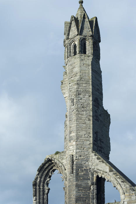 Stately stone remnant of St Andrews Cathedral ruins, Scotland with part of tall spire and Gothic window arch against a hazy sky