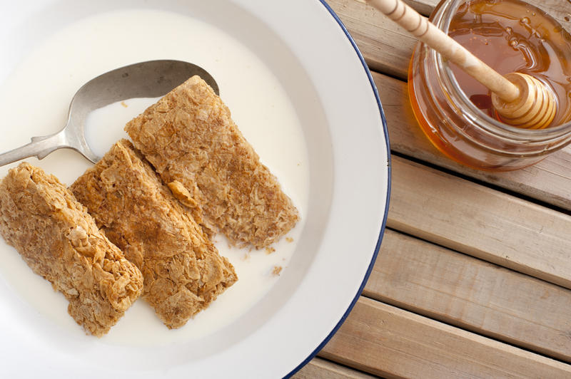 whole wheat breakfast cereal in an enamel bowl with milk and honey