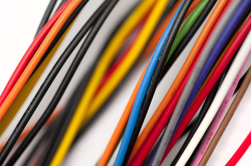 Close up on various colored wires going across frame with some out of focus over white background