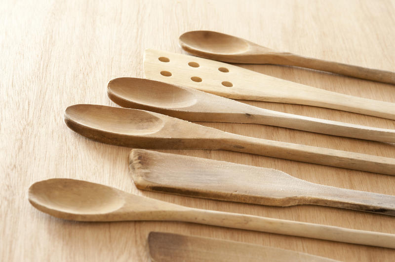 Set of wooden kitchen spoons and spatulas laid out in a neat row on a wooden cutting board or table