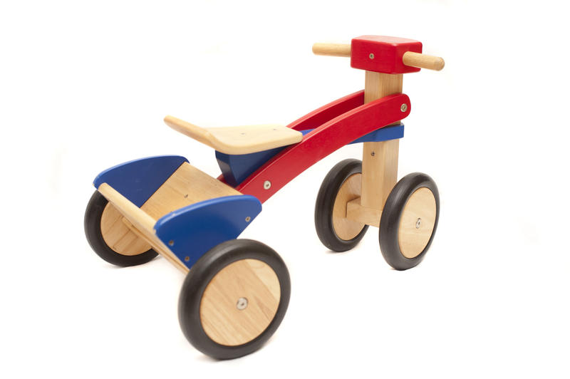 Kids wooden toy tricycle with colorful red and blue paintwork isolated on white with copy space