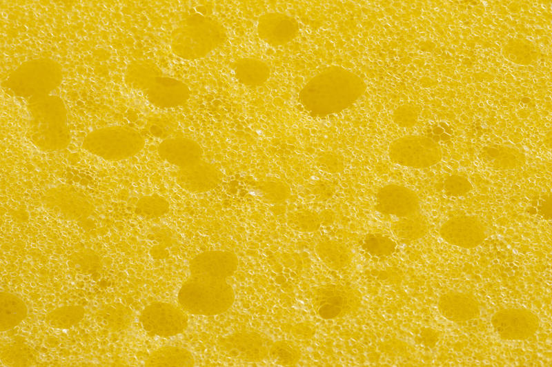 Close up macro of the surface of a sponge in a full frame background texture showing the myriad of small porous holes