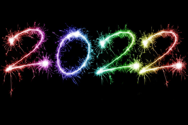 rainbow coloured sparkling fireworks as happy new year holiday 2022 over black background