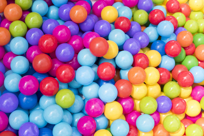 Full frame background of brightly colored balls in the colours of the rainbow in a ball pit at an amusement park