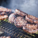 17231   Beef burger patties and sausage on a BBQ