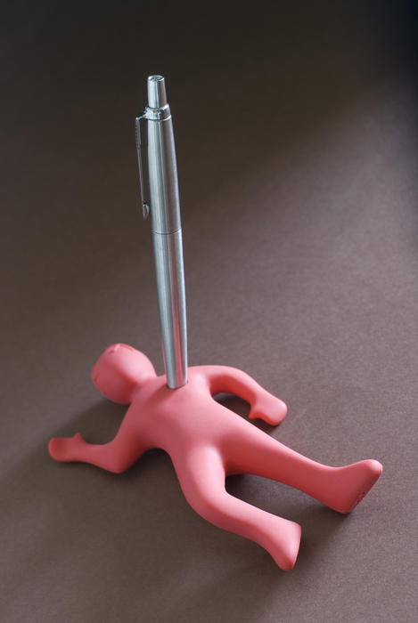 Small pink man figure stabbed to dead with a metal pen as a concept for business troubles