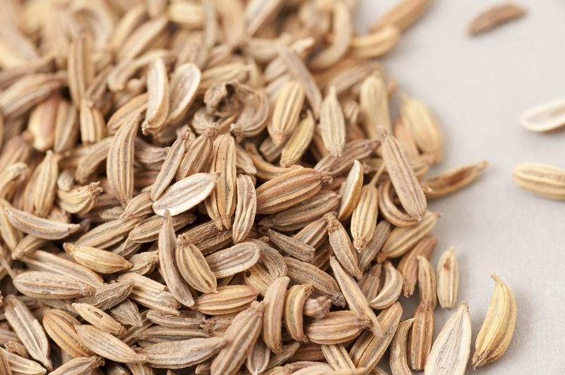Macro view of loose dried caraway seeds heaped on white, an aromatic herb for cooking