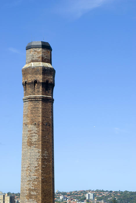 Old brick industrial chimney top or smokestack against blue sky with copy space