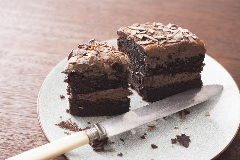 Remaining slices of an iced chocolate sponge cake on a plate with crumbs and knife