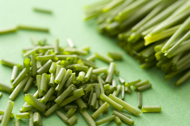 Heap of chopped fresh chives on a green chopping board in close for use in salads or as a garnish