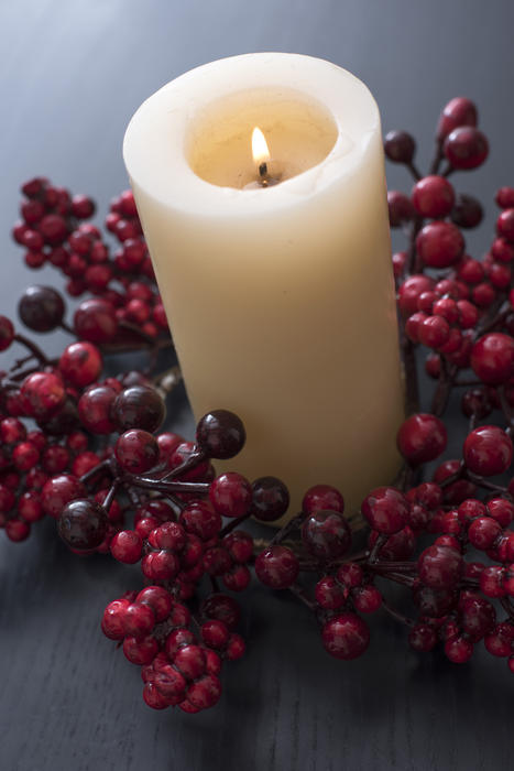 a festive table centre with a chruch candle and red berry wreath