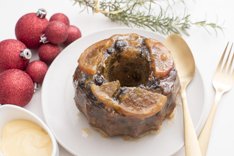 close up view of a christmas fruit pudding with preserved fruit decoration on a plate