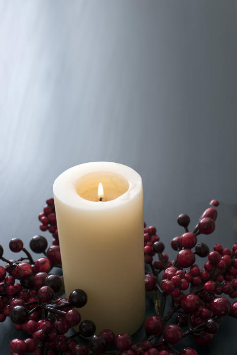 a christmas berry wreath with large burning chruch candle at the centre for advent