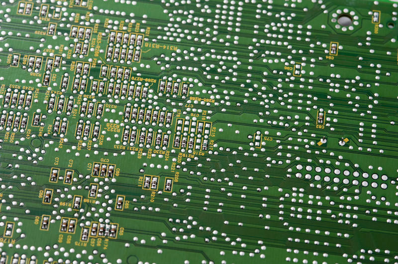 Detail of a green printed electronic circuit board wiring and components in a full frame view