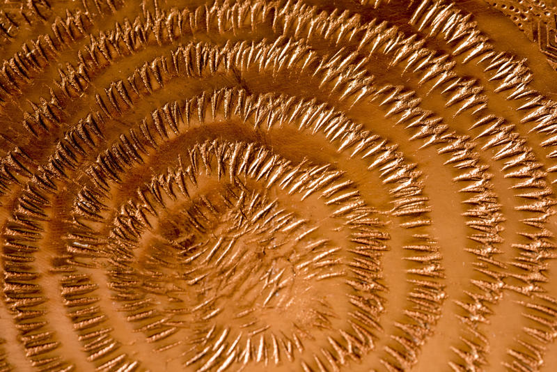 Decorative beaten circular pattern on sheet metal copper in a close up full frame view