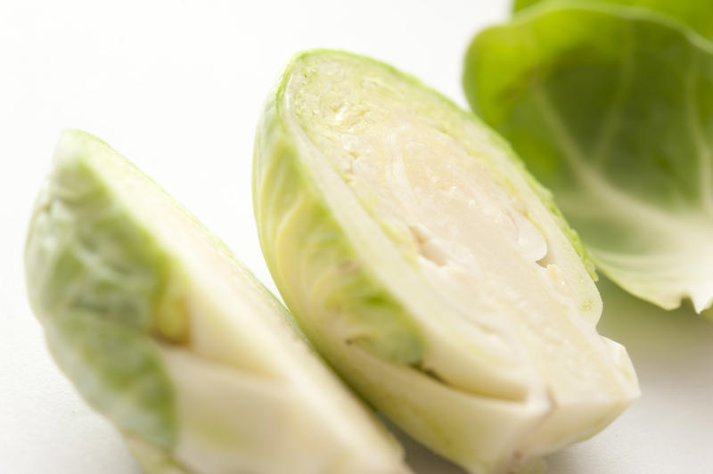 Macro close-up of fresh raw Brussels sprouts cut in half, on white surface background