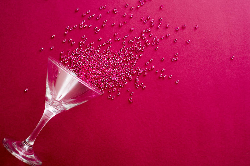 Cocktail glass party background on a festive red background with spilled beads in a decorative pattern and copy space