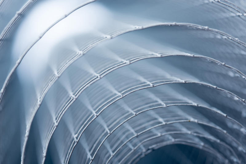 Abstract artistic view of a coil or roll of metal mesh viewed end on so that the edges form a pattern of concentric circles with shallow dof