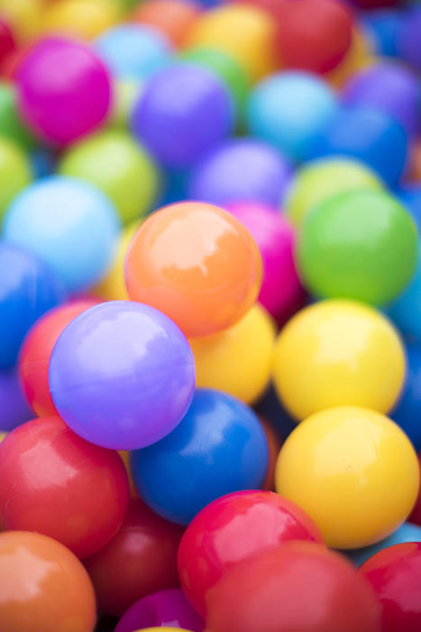 Close up on a heap of colorful plastic balls in the colors of the rainbow with shallow dof and copy space