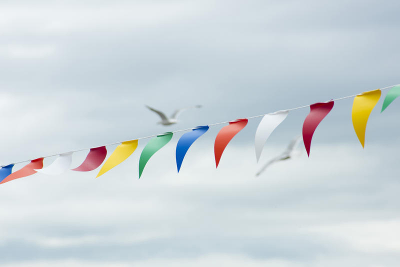 Brightly colored bunting with triangular flags to celebrate a festive event flying in the wind against a grey cloudy sky with copy space