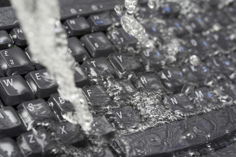 Concept of IT transparency with fresh water pouring over a submerged black computer keyboard in a full frame view