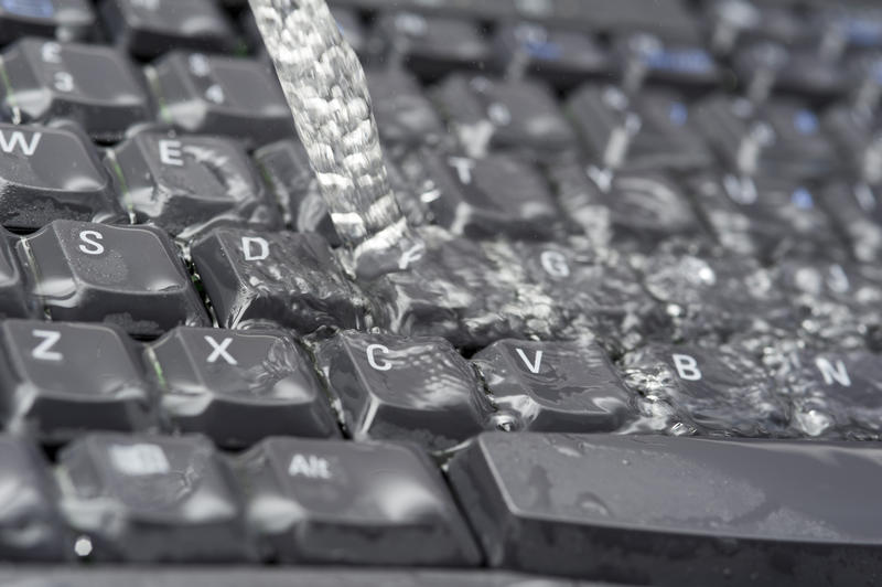 Running water damage to the black computer keyboard, viewed in close-up
